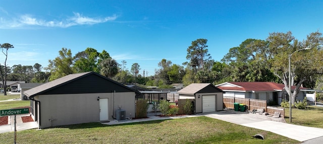 view of front of house with cooling unit, fence, concrete driveway, stucco siding, and a front yard