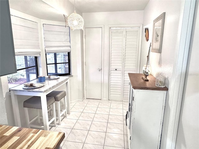 kitchen with white cabinets, decorative light fixtures, and light tile patterned flooring