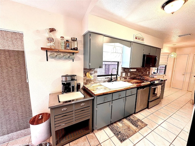 kitchen featuring gray cabinetry, a sink, visible vents, appliances with stainless steel finishes, and backsplash