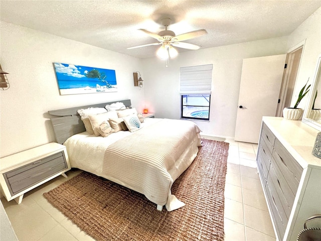 bedroom with a textured ceiling, ceiling fan, and light tile patterned floors