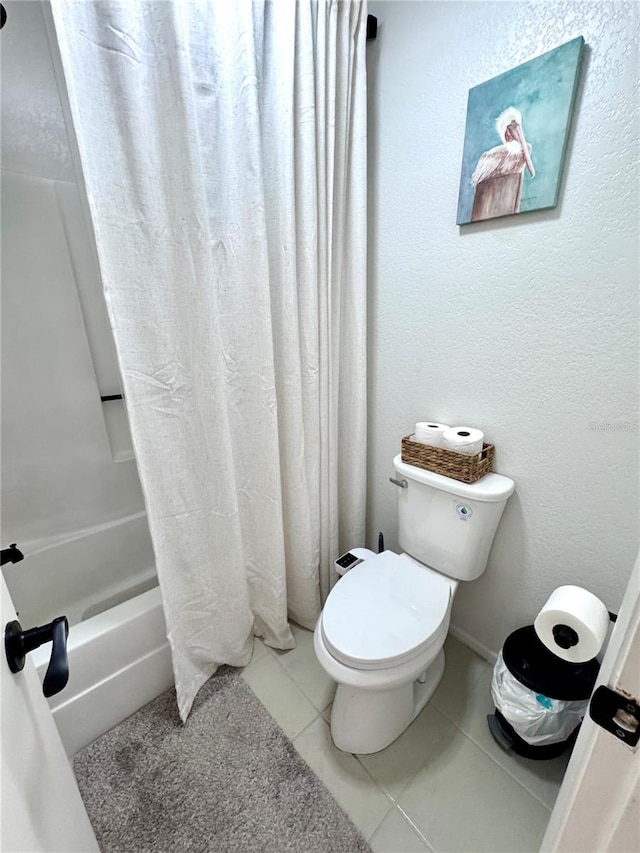 bathroom featuring shower / bath combination with curtain, tile patterned flooring, a textured wall, and toilet