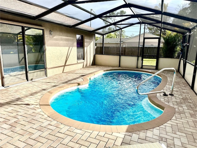 view of swimming pool featuring glass enclosure, fence, a fenced in pool, and a patio