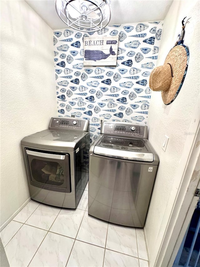 washroom with laundry area, washing machine and dryer, marble finish floor, and baseboards