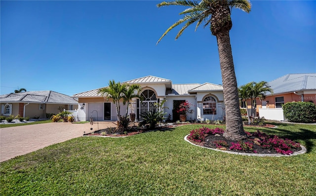 view of front of home featuring stucco siding, metal roof, decorative driveway, and a standing seam roof