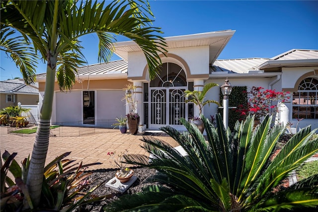 view of front of property with metal roof, a patio, a standing seam roof, and stucco siding