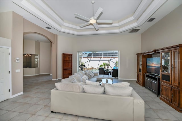 living area with a tray ceiling, visible vents, and a towering ceiling