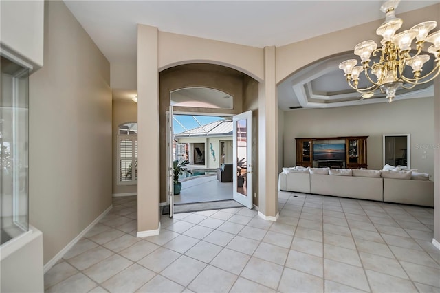 entrance foyer with a notable chandelier, light tile patterned floors, and baseboards