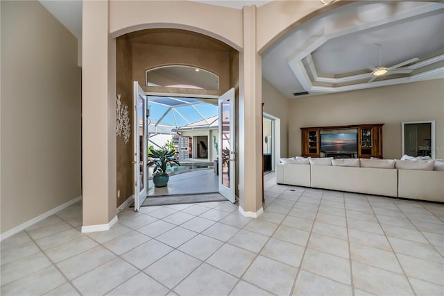 foyer with light tile patterned floors, baseboards, a raised ceiling, and a ceiling fan