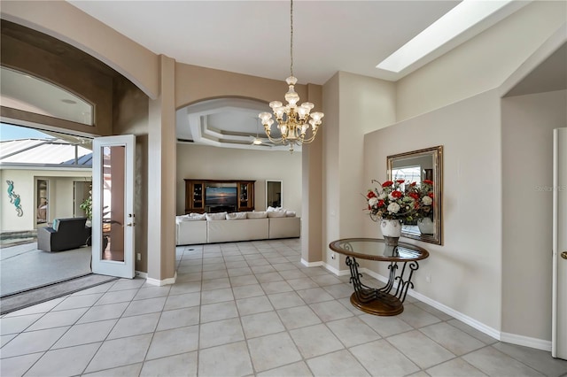 entryway with a notable chandelier, light tile patterned floors, and baseboards