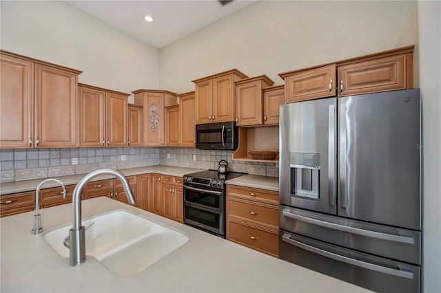 kitchen with decorative backsplash, stainless steel appliances, light countertops, and a sink