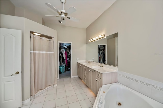 full bathroom featuring a tub with jets, double vanity, a sink, tile patterned flooring, and a walk in closet