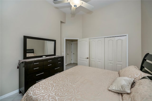 bedroom with a closet, ceiling fan, a high ceiling, and baseboards