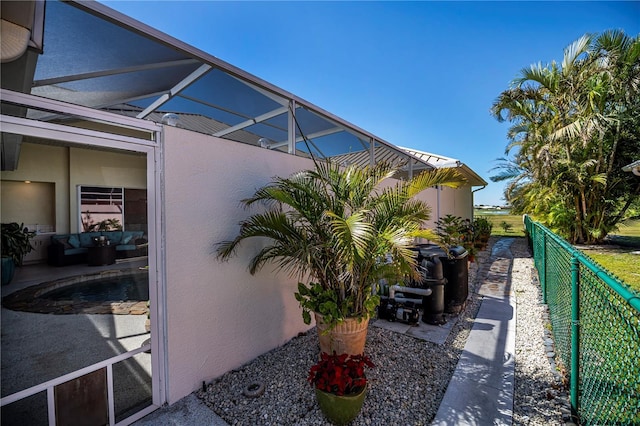 view of home's exterior featuring stucco siding, a lanai, and fence