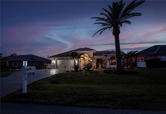 ranch-style home with a standing seam roof, stucco siding, a front lawn, decorative driveway, and metal roof