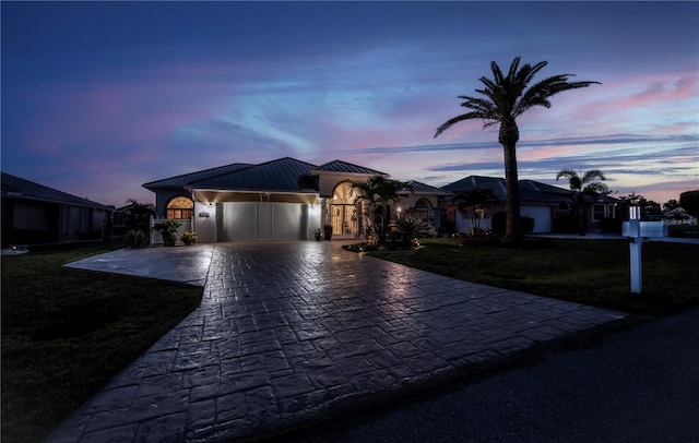 view of front of house featuring a lawn, a standing seam roof, decorative driveway, an attached garage, and metal roof