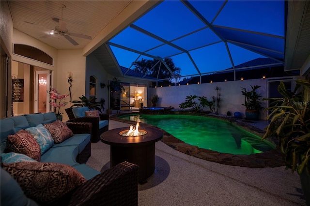 pool at twilight with a pool with connected hot tub, an outdoor living space with a fire pit, glass enclosure, a patio area, and a ceiling fan