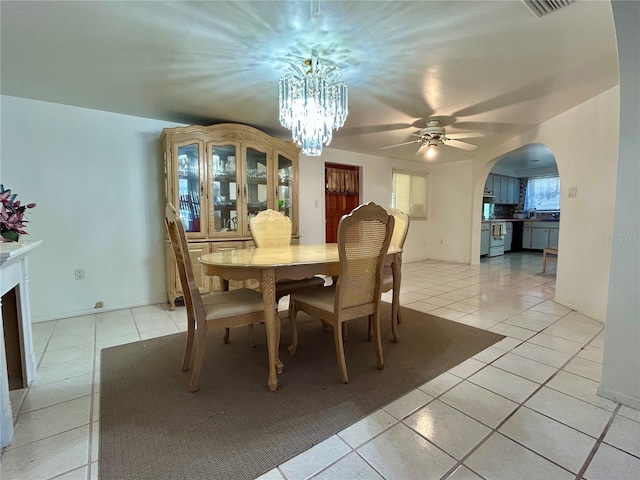 dining area featuring light tile patterned floors, a fireplace, arched walkways, and a notable chandelier