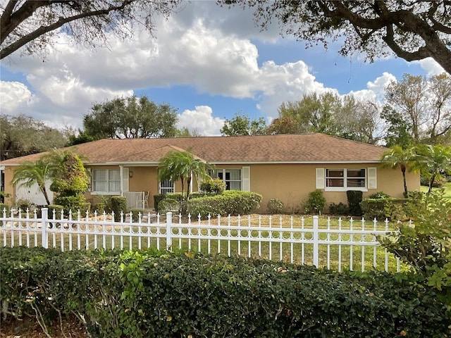 ranch-style house featuring a front lawn, a fenced front yard, and stucco siding