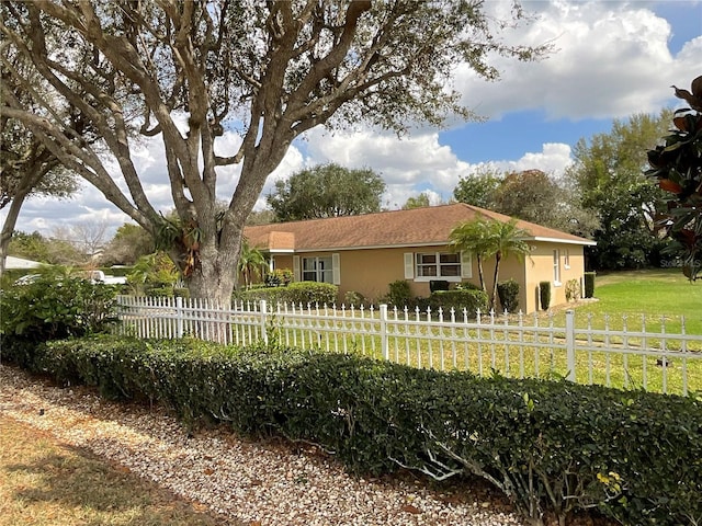 ranch-style home with a front yard, fence, and stucco siding