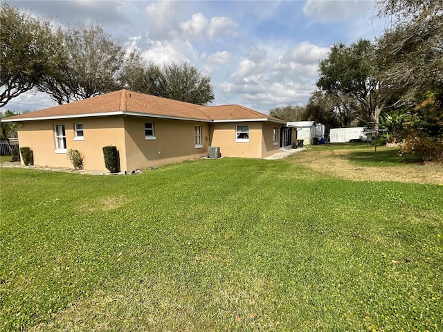 back of house featuring fence, a lawn, cooling unit, and stucco siding