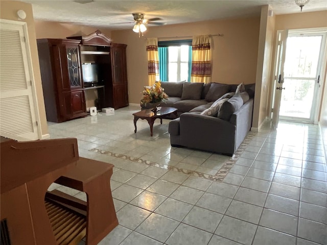 living area featuring ceiling fan, baseboards, and light tile patterned floors