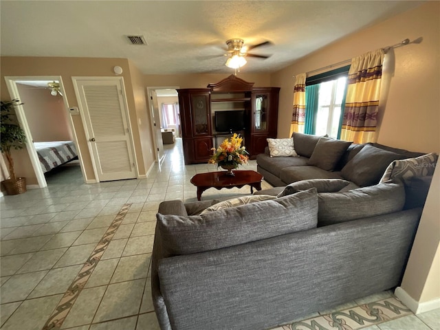 living room with light tile patterned floors, baseboards, visible vents, and ceiling fan