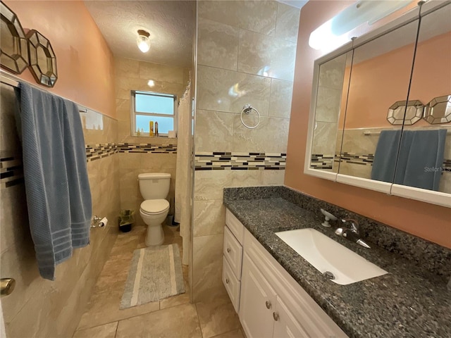full bath with tile walls, toilet, vanity, a shower with curtain, and tile patterned floors