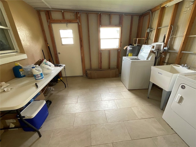 laundry room featuring light tile patterned floors, laundry area, washer and clothes dryer, and a sink