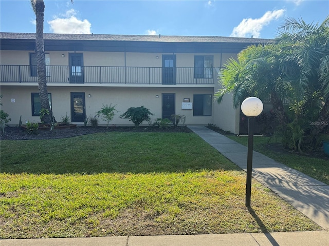 townhome / multi-family property featuring a front lawn and stucco siding