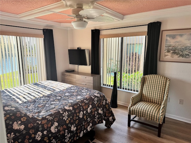 bedroom featuring baseboards, ornamental molding, coffered ceiling, and wood finished floors