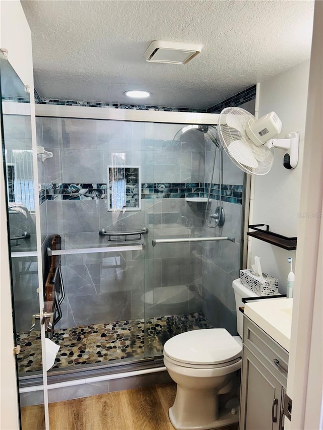 full bathroom featuring vanity, wood finished floors, toilet, and a shower stall