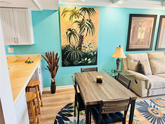 interior space featuring ornamental molding, baseboards, a textured wall, and light wood finished floors