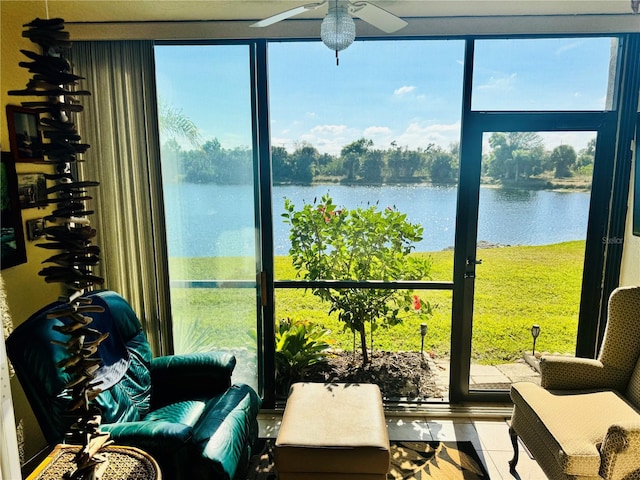 sunroom with a ceiling fan and a water view