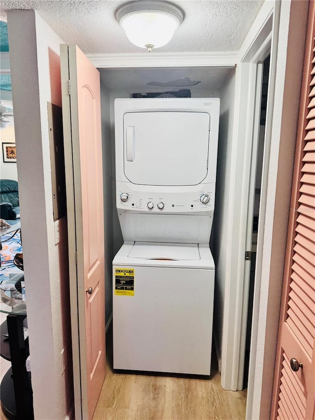 washroom with stacked washer and dryer, a textured ceiling, laundry area, and light wood-style floors