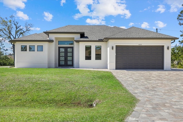 prairie-style house featuring roof with shingles, an attached garage, decorative driveway, french doors, and a front yard