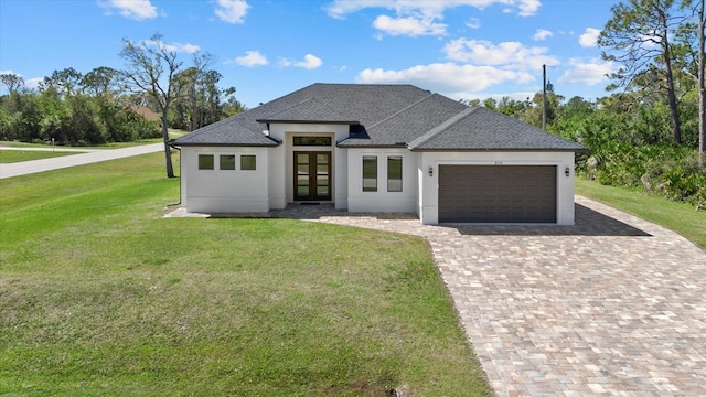 view of front of house featuring decorative driveway, french doors, roof with shingles, an attached garage, and a front yard