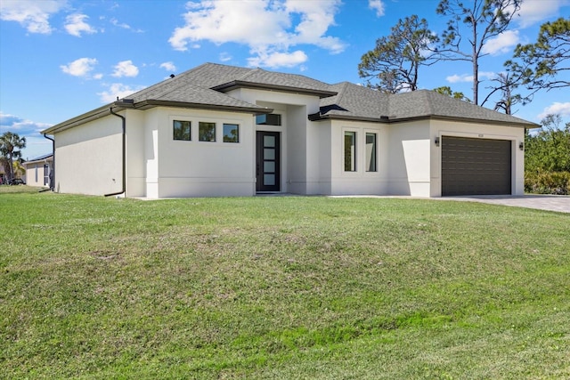 prairie-style house with driveway, stucco siding, an attached garage, and a front yard