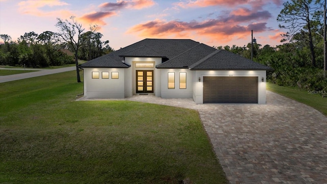 view of front of house featuring a garage, a shingled roof, french doors, decorative driveway, and a yard