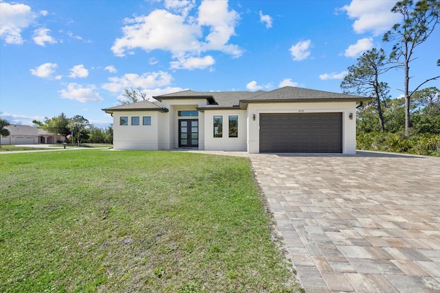 prairie-style house featuring decorative driveway, french doors, stucco siding, a front yard, and a garage