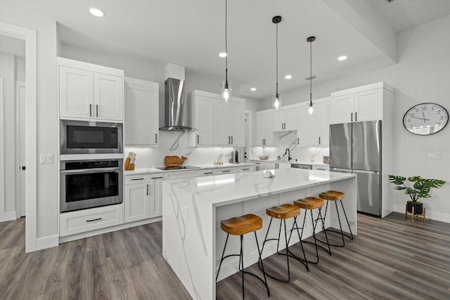 kitchen featuring white cabinets, dark wood finished floors, wall chimney exhaust hood, a center island, and stainless steel appliances