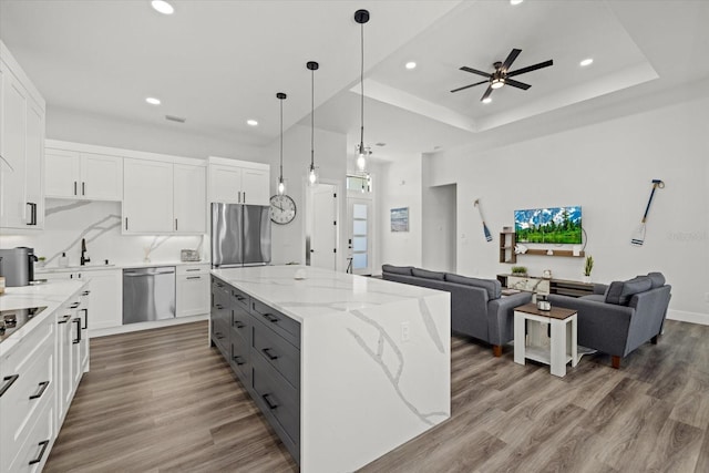 kitchen with stainless steel appliances, gray cabinetry, open floor plan, white cabinetry, and wood finished floors