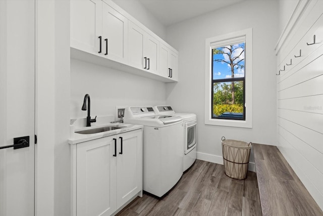 laundry room with washing machine and clothes dryer, cabinet space, dark wood-type flooring, a sink, and baseboards