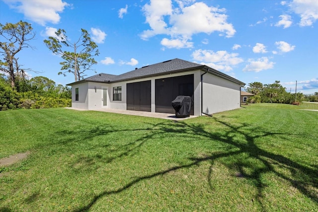 back of house featuring a sunroom, stucco siding, a patio, and a yard