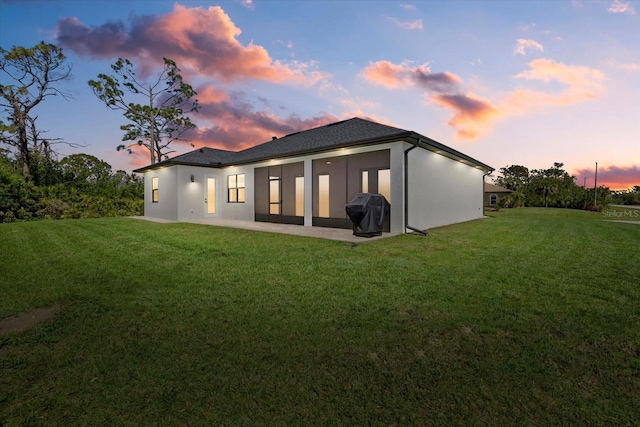 rear view of property featuring a patio area, stucco siding, and a yard