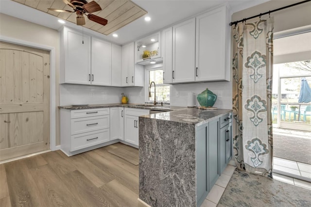 kitchen with stone countertops, white cabinets, light wood finished floors, and tasteful backsplash