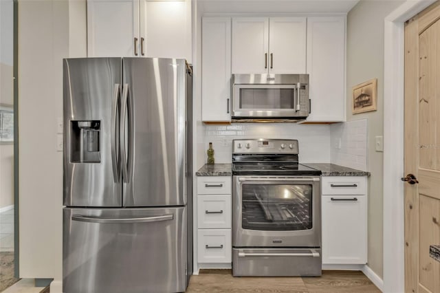 kitchen featuring backsplash, appliances with stainless steel finishes, white cabinets, and dark stone countertops