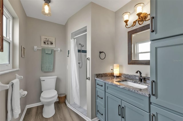 bathroom featuring toilet, a shower with shower curtain, wood finished floors, vanity, and baseboards