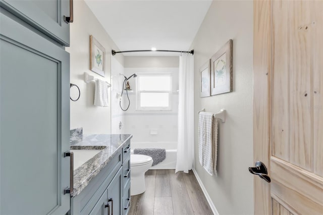 full bath featuring baseboards, toilet, shower / tub combo with curtain, wood finished floors, and vanity