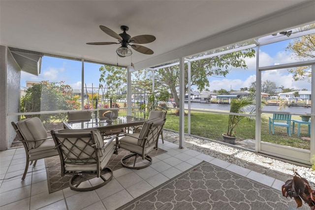 sunroom / solarium featuring a water view and ceiling fan