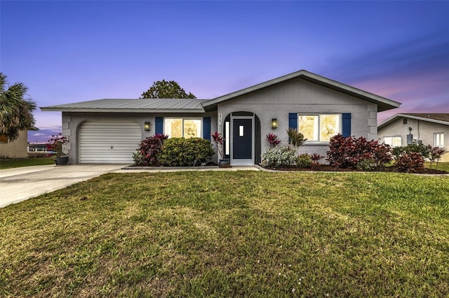 ranch-style home featuring a garage, stucco siding, driveway, and a lawn